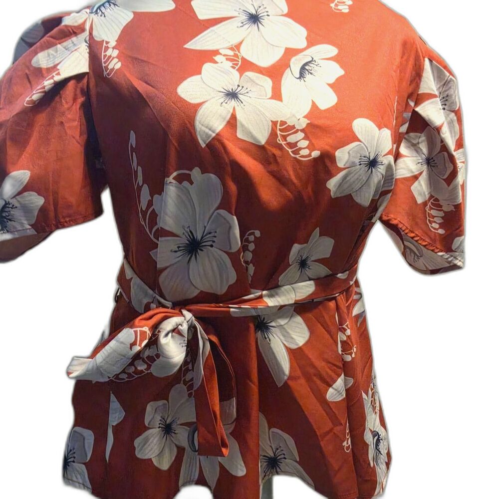 rust-orange peplum-style wrap top with a white floral pattern